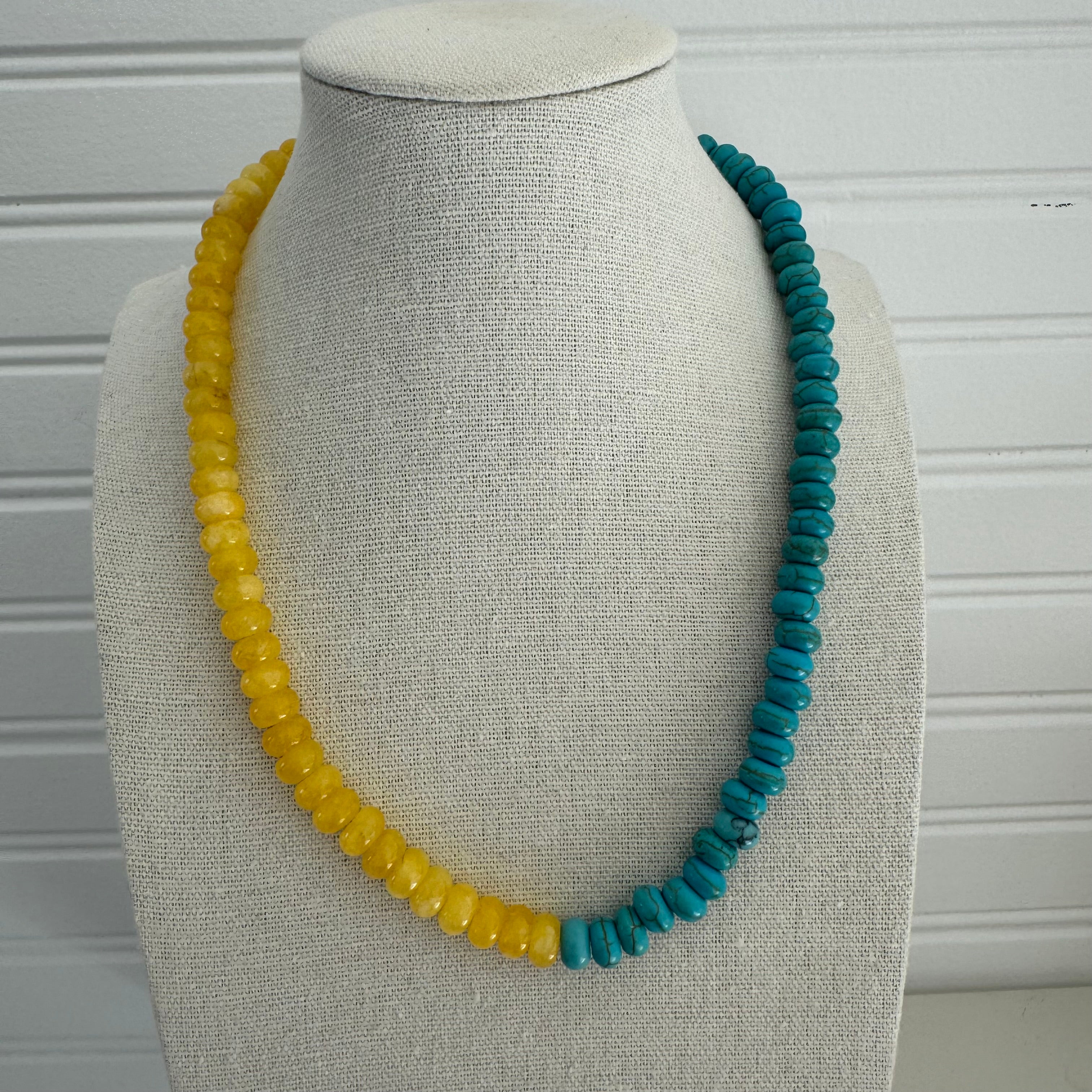 Picture of a bead necklace that is two colors. One half is a bold sunflower yellow and the other turquoise.