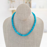 A turquoise gemstone necklace with a gold carabiner clasp, displayed on a mannequin.