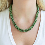 Woven green plastic rope necklace on a person wearing a white top