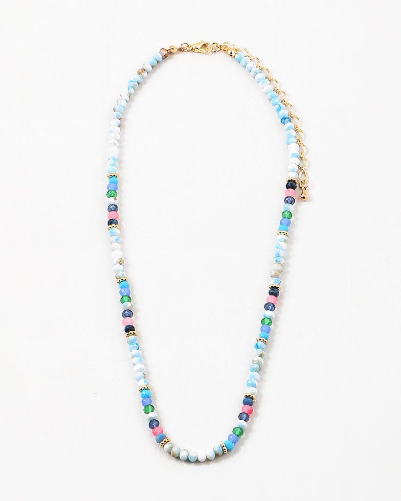 Bead necklace made of mostly variegated shades of blues with pink and gold spacer beads.