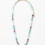 Bead necklace made of mostly variegated shades of blues with pink and gold spacer beads.