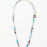 Bead necklace made of mostly variegated shades of blues with pink and gold spacer beads.