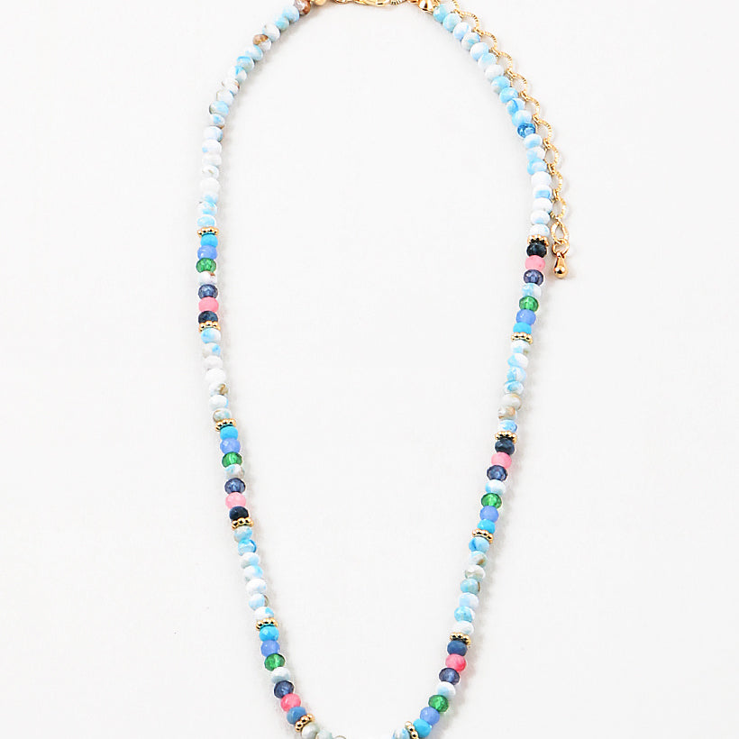 Bead necklace made of mostly variegated shades of blues with pink and gold spacer beads.