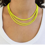 Necklace with three yellow chains on a person wearing a white top.