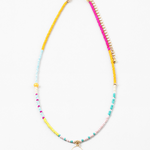 Small bead necklace in yellow, pink, turquoise and white beads. Necklace has a small white enamel disc pendant at its center.