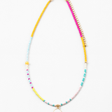 Small bead necklace in yellow, pink, turquoise and white beads. Necklace has a small white enamel disc pendant at its center.
