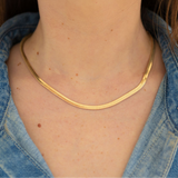 Gold herringbone chain necklace on a person wearing a button up denim shirt
