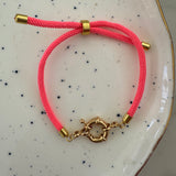 Pink bracelet with gold clasp on a speckled ceramic plate