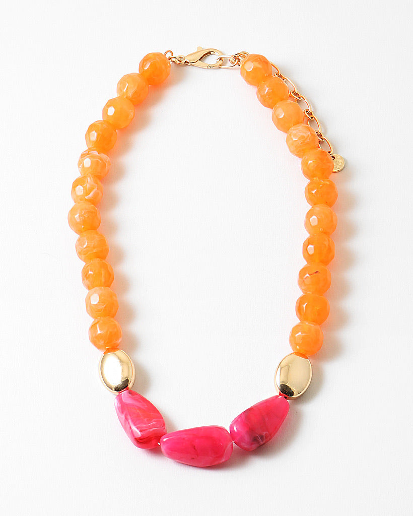 Necklace with orange beads and large pink beads on a white background