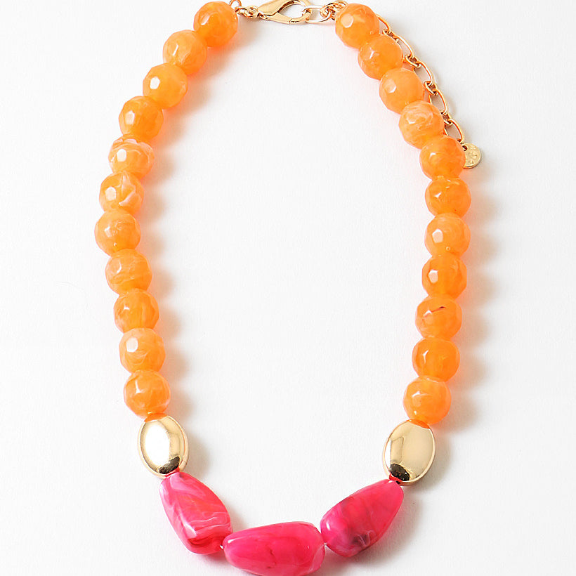 Necklace with orange beads and large pink beads on a white background