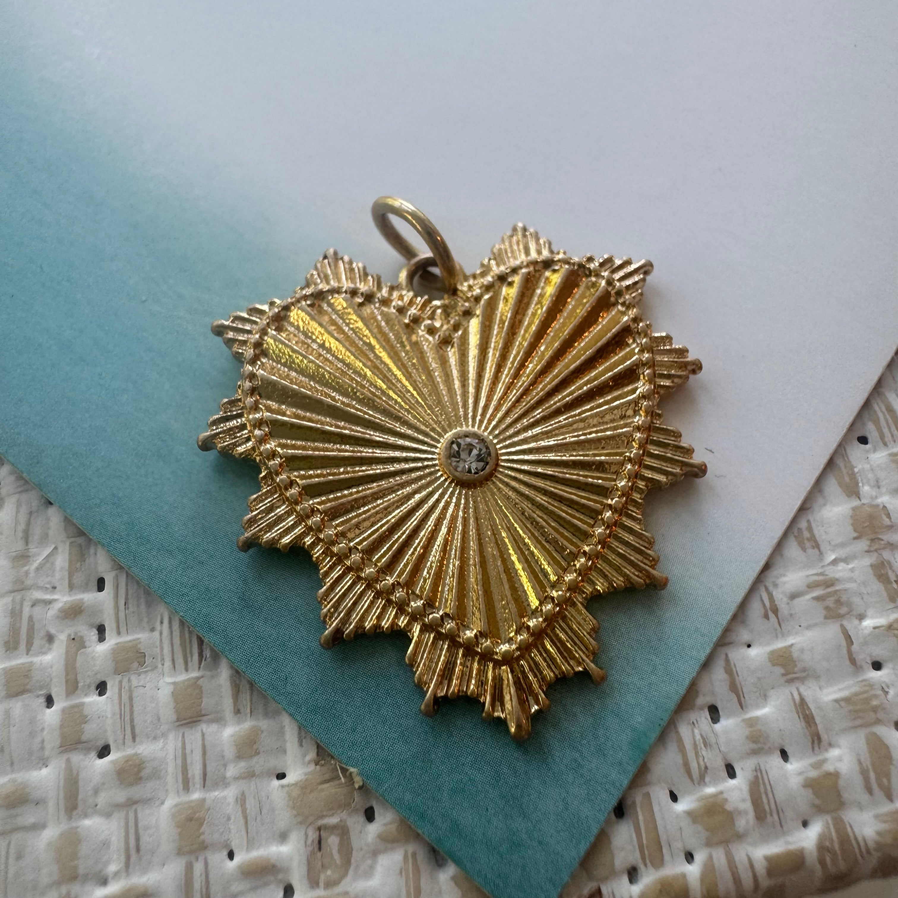 Close up picture of a textured gold heart charm with a central diamond.