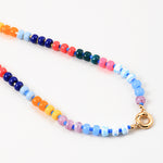 Bead necklace made of navy, pink, orange, yellow and light blue beads. Center of the necklace has a large gold clasp.
