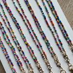 Picture of 8 multicolored beaded lanyards with gold clasps lined up next to each other.
