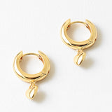 Gold hoop earrings with a small heart pendant on a white background