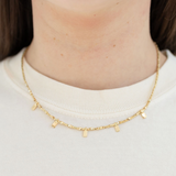 Gold necklace with gold tabs worn by a person on a white background