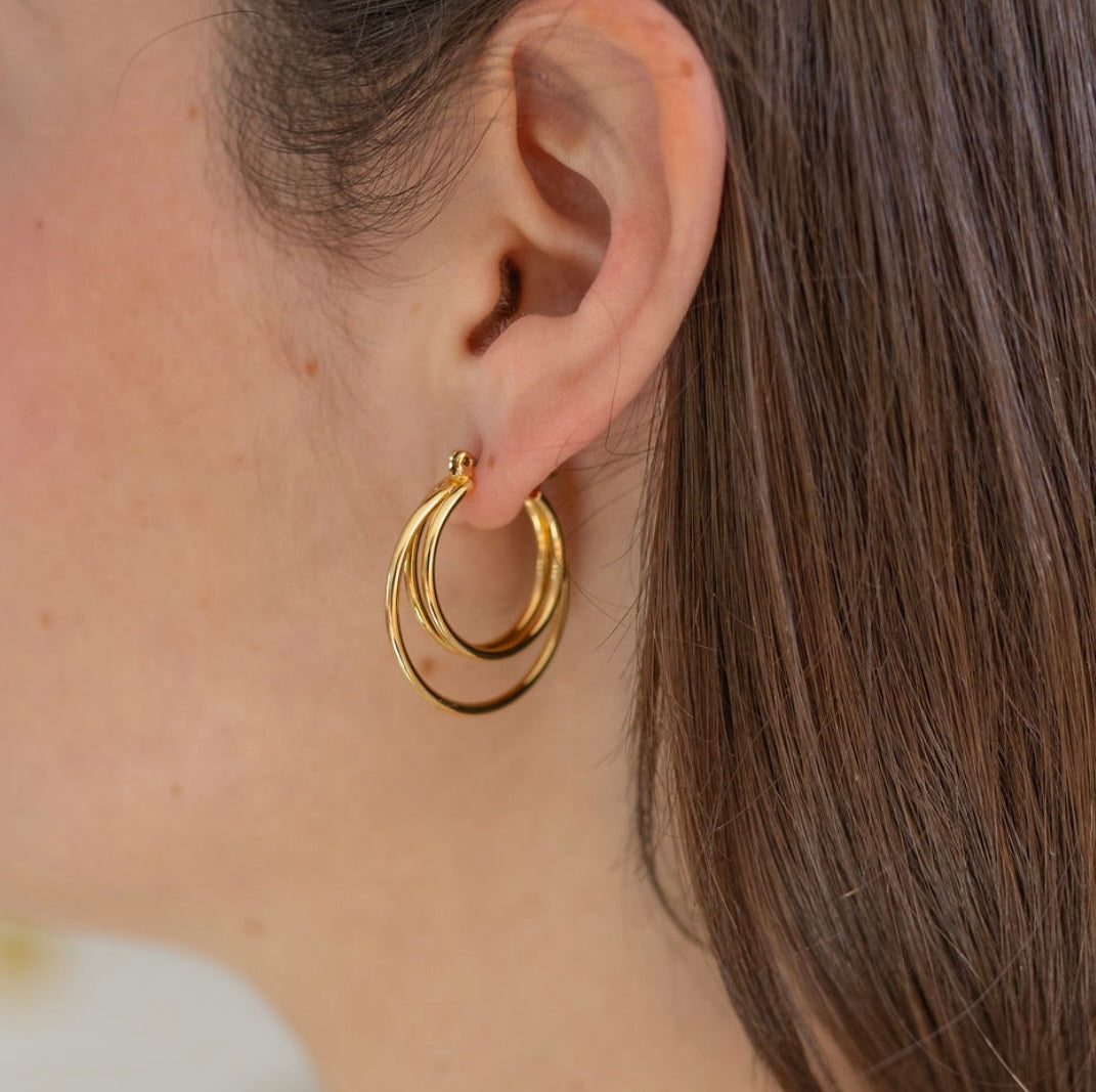 Picture of model wearing gold earrings made of three hoops.