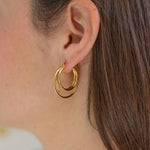 Picture of model wearing gold earrings made of three hoops.