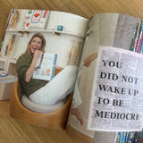 Open magazine with a woman on one page and text on the other, on a wooden surface.