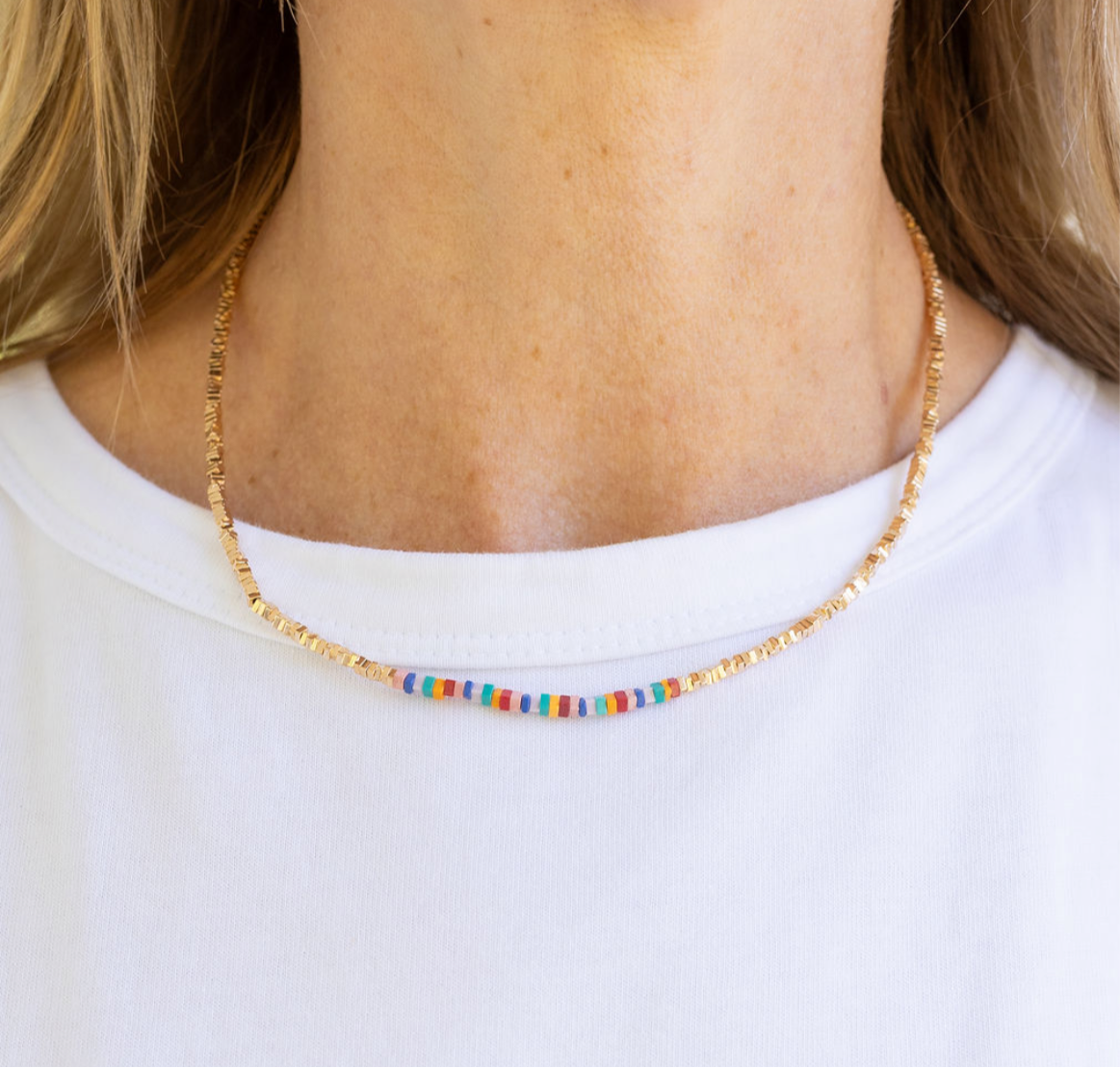Picture of a dainty gold seed bead necklace with central blue, red and yellow beads.