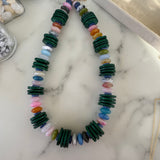 Colorful beaded necklace with dark green wooden disc beads on a marble surface