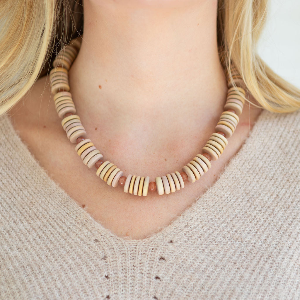 Necklace with wooden beads worn by a person with blonde hair.