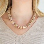 Necklace with wooden beads worn by a person with blonde hair.