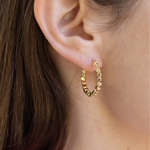 Gold hoop with square gold earrings worn by a person with brown hair.