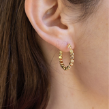 Gold hoop with square gold earrings worn by a person with brown hair.