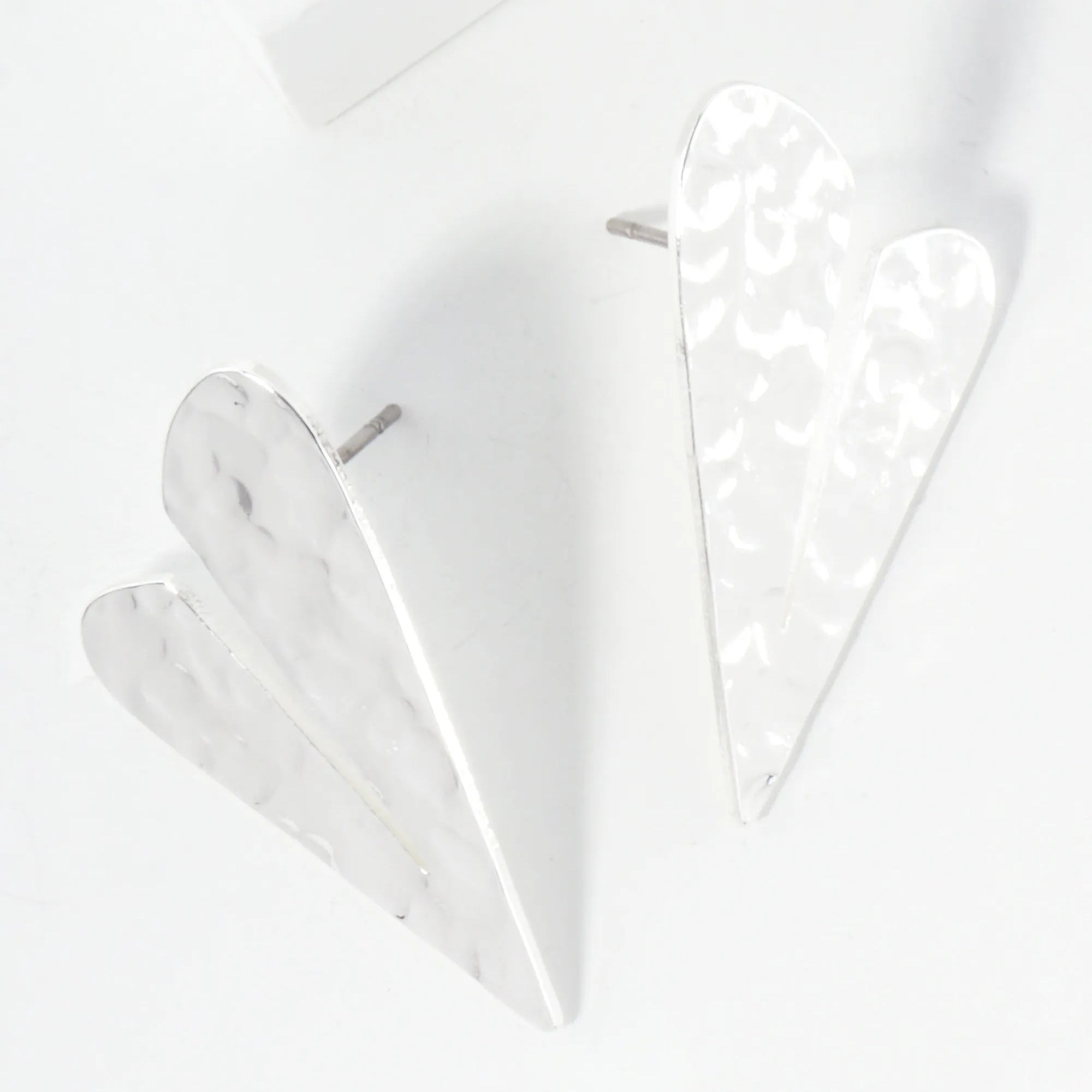 Set of two white geometric heart-shaped earrings on a light gray background