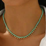 Picture of model wearing a small turquoise beaded necklace with tiny gold dangling beads at the front.