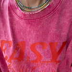Picture of a woman wearing a pink Tshirt and three dainty bead necklaces. One necklace is yellow and white, one in dark and light blues and one in white and gold.