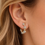 Close-up of an ear wearing a gold earring with blue gemstones.