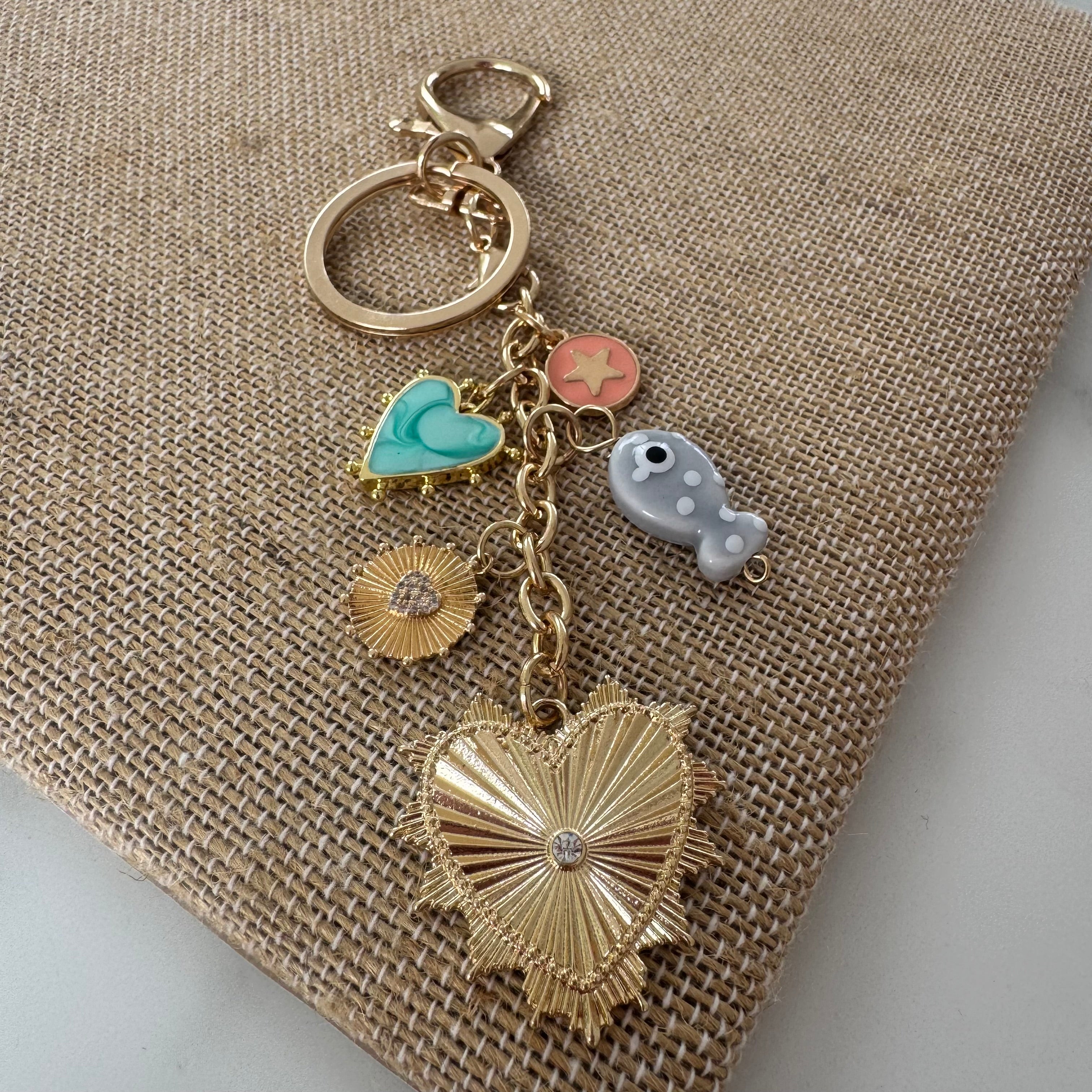 Keychain with heart-shaped charm and various other charms on a textured surface