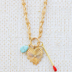 Picture of gold toggle chain with a turquoise teardrop, a large gold heart pendant with a diamond center and a gold matchstick.