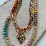 Set of three necklaces made up of small colorful bead necklace, a gold chain link with hammered gold heart pendant and a larger colorful beaded necklace.
