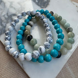 Set of beaded bracelets with turquoise, white, and green beads on a marble surface.