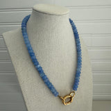 Picture of a periwinkle blue beaded necklace with a large gold carabiner clasp.