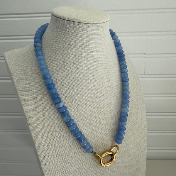 Picture of a periwinkle blue beaded necklace with a large gold carabiner clasp.