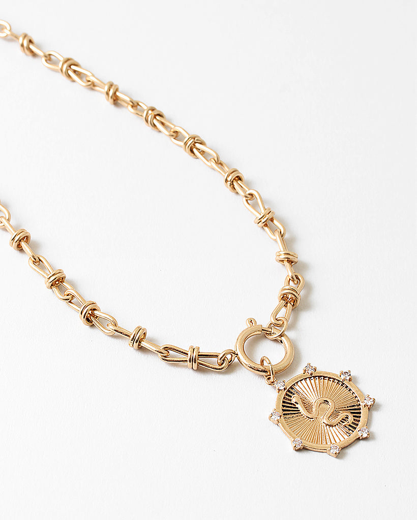 Gold chain bracelet with a decorative charm on a white background