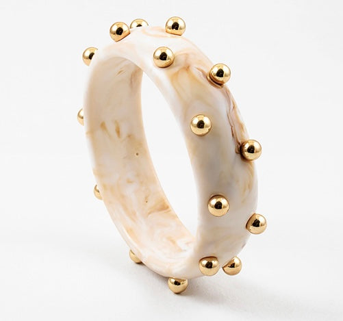 Picture of a marbled ivory colored bangle with inlaid gold beads.