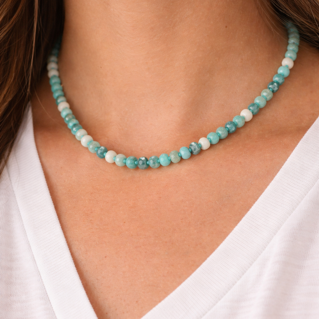 Necklace with small turquoise beads worn by a person in a white shirt