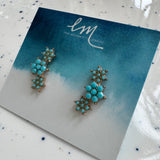 Pair of turquoise earrings on a branded card with a blue watercolor design.