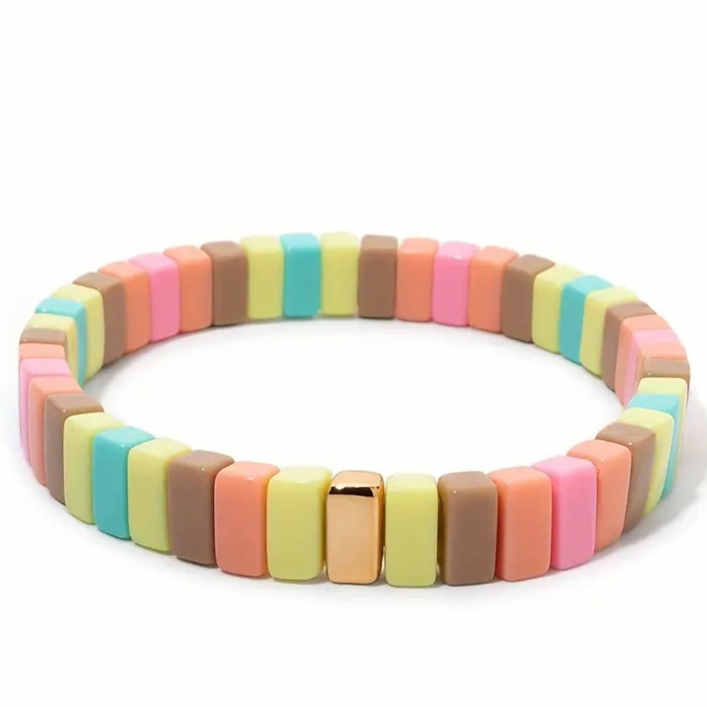 Colorful bracelet in pastel yellows, corals and browns with gold beads on a white background