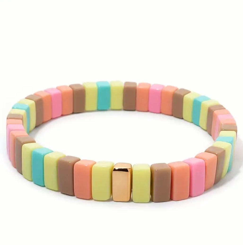 Colorful bracelet in pastel yellows, corals and browns with gold beads on a white background