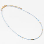 Dainty bead necklace with clear blue beads, gold and some solid blue beads.