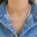 Person wearing a clear beaded necklace with a denim jacket