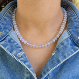Person wearing a clear beaded necklace with a denim jacket