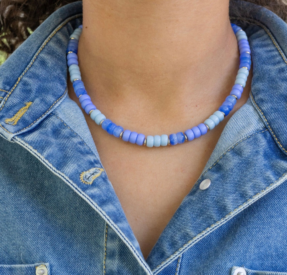 Person wearing a blue beaded necklace with a denim jacket