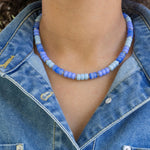 Person wearing a blue beaded necklace with a denim jacket
