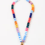 Bead necklace made out of navy blue, orange, yellow, purple and blue beads. Necklace has a large gold clasp at its center.